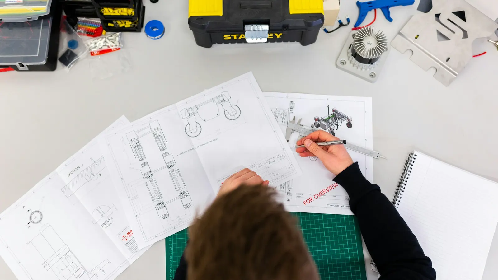 Ingenieur arbeitet an technischen Zeichnungen auf einem Werkstatttisch