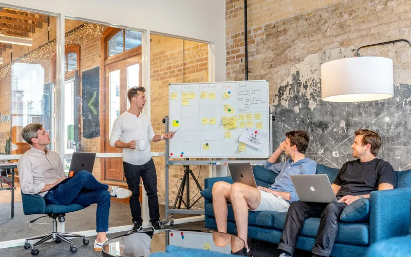 Drei Personen besprechen eine Marketingplanung an einem Whiteboard mit Haftnotizen