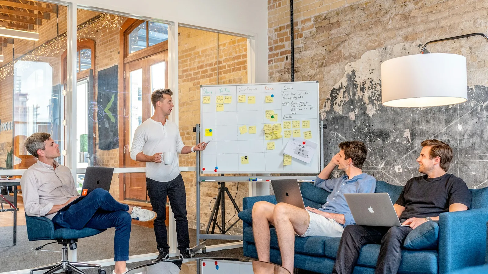 Drei Personen besprechen eine Marketingplanung an einem Whiteboard mit Haftnotizen
