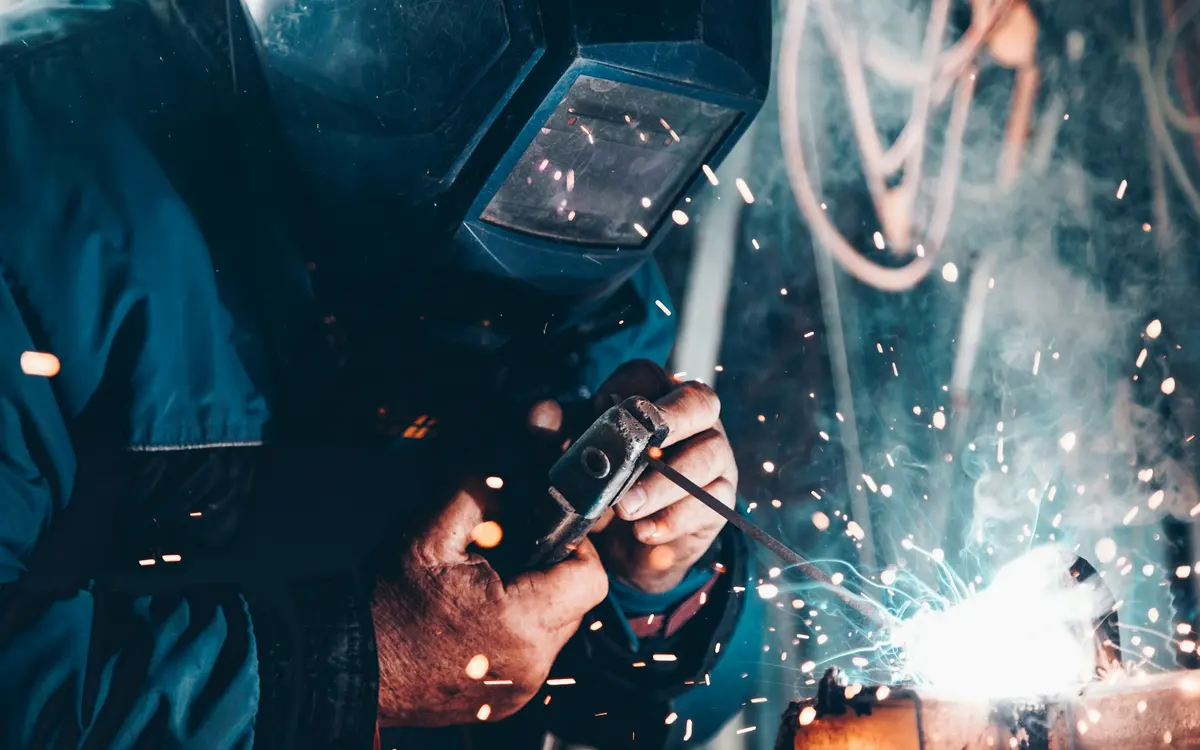 Schweißer arbeitet mit Schutzmaske an einem Metallbauteil