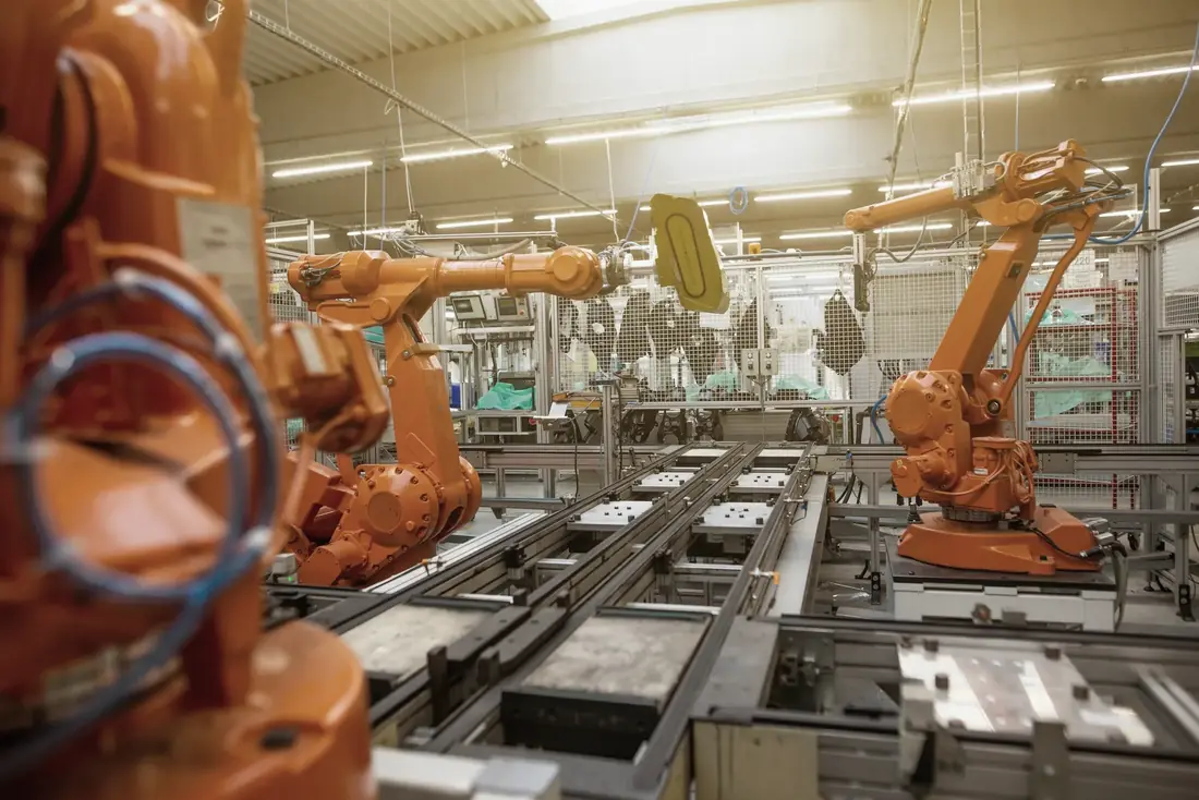 Orangefarbene Industrieroboter an einer automatisierten Fertigungslinie